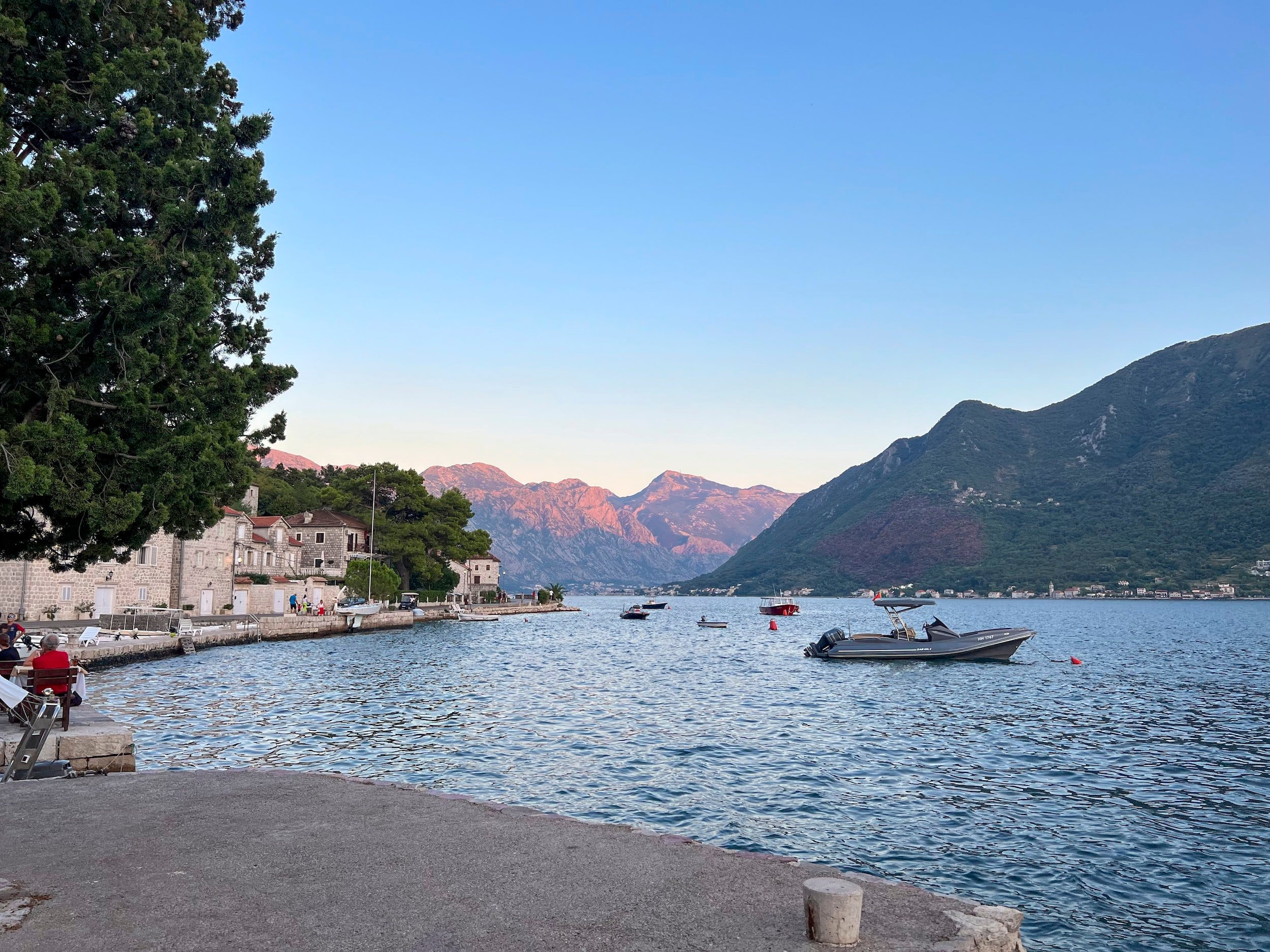 Calm waters of kotor bay at sunset surrounded by sun-kissed mountain tops