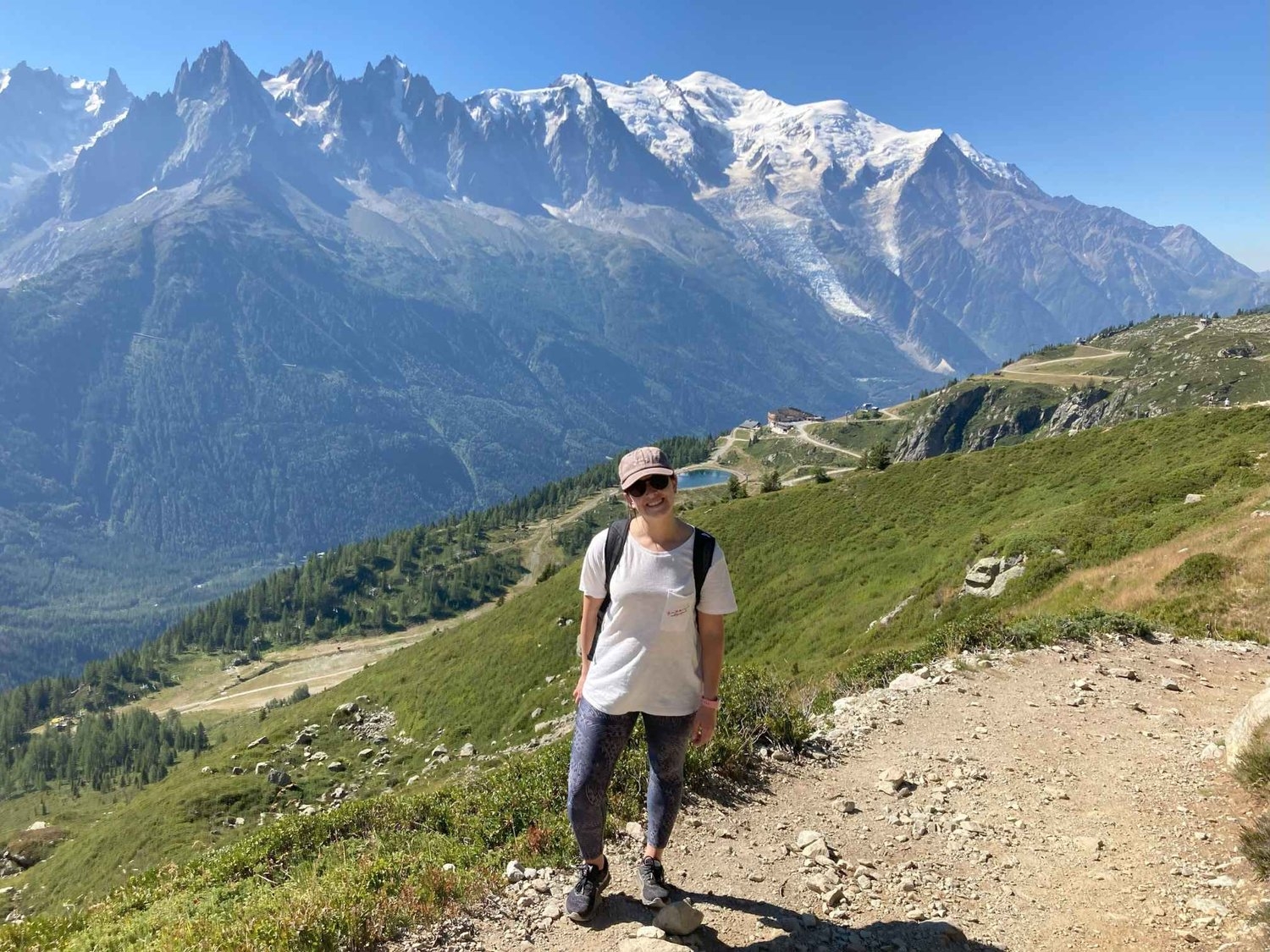 female hiker standing on top of boulder on easy lac blanc hike route in front of mont blanc mountain range