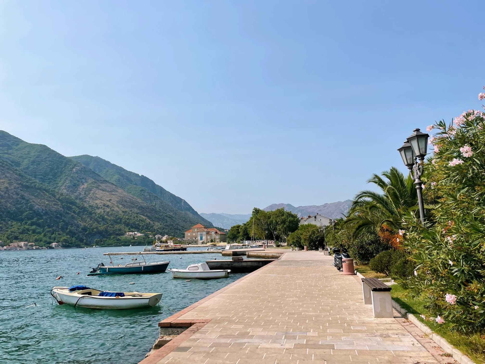 Boats in the quiet Bay of Kotor surrounded by mountains and blue skies