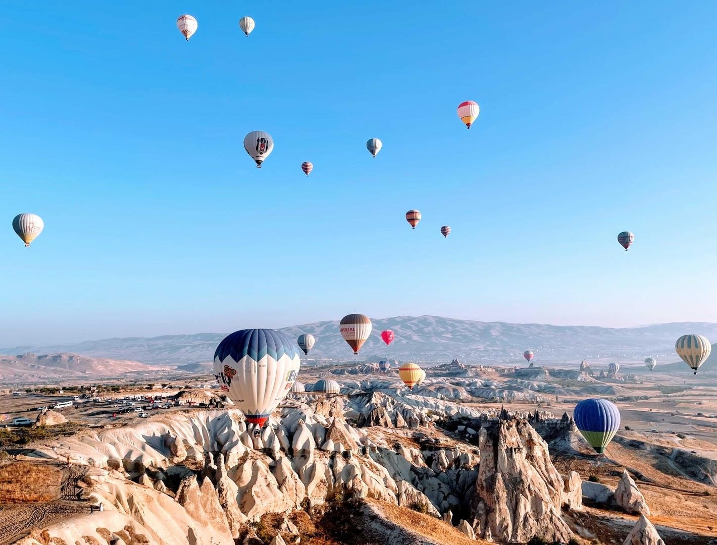 Colourful hot air balloons floating over rock formations in Cappadocia at sunrise